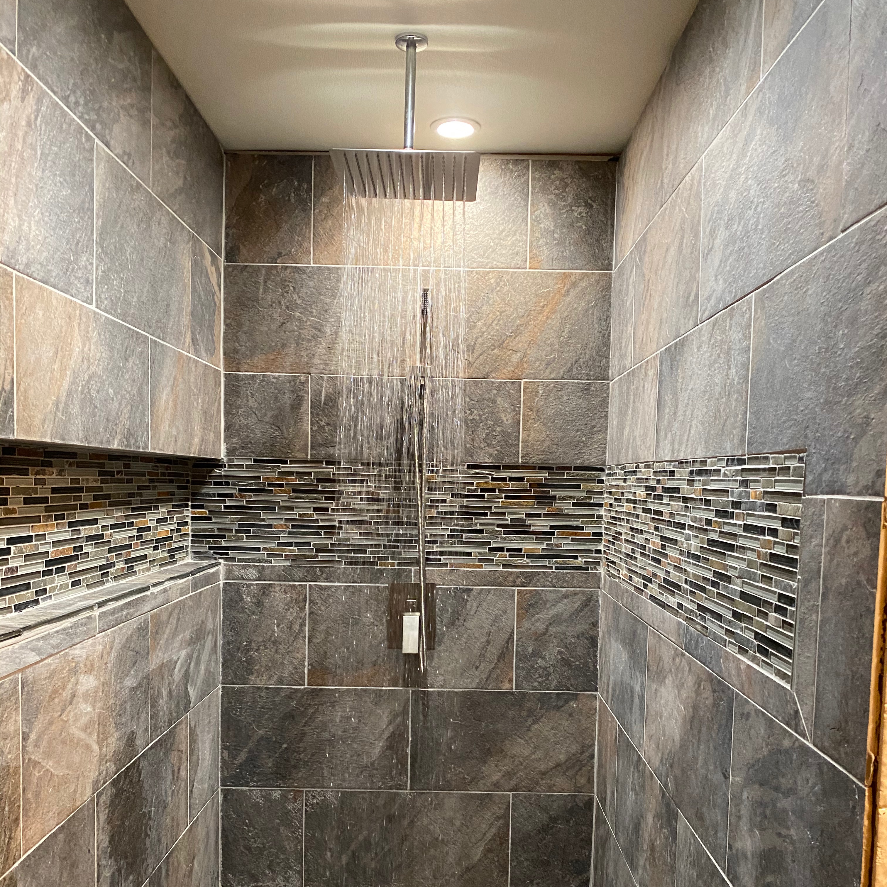 A walk in shower sitting next to a tiled wall